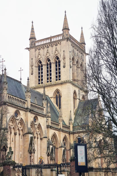 London, United Kingdom, January 17, 2025: Gothic cathedral features intricate stonework and towering spires standing against a winter sky. the bare trees and overcast atmosphere enhance the structure's historical and architectural grandeur.