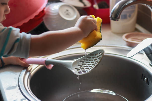 istock Little boy washes dishes and so happy 2203395118
