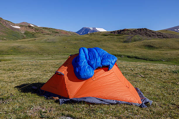 istock A blue down sleeping bag is drying on an orange tent in the mountains. 2203397002