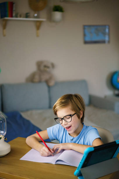 istock Happy boy whit eyeglasses writing homework 2203398599