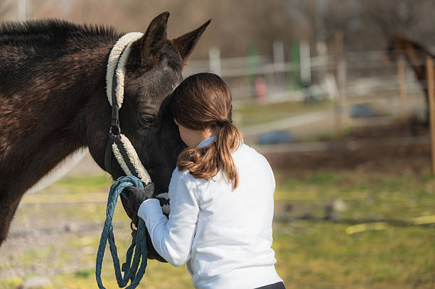 istock Young horse rider embracing her horse in a paddock 2203399071
