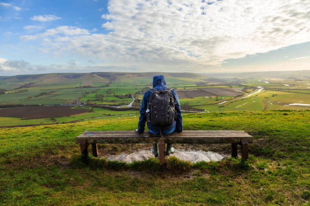 istock Hiker sitting on bench looking at view on South Downs in southeast England 2203399080