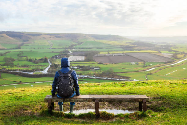 istock Hiker sitting on bench looking at view on South Downs in southeast England 2203399124