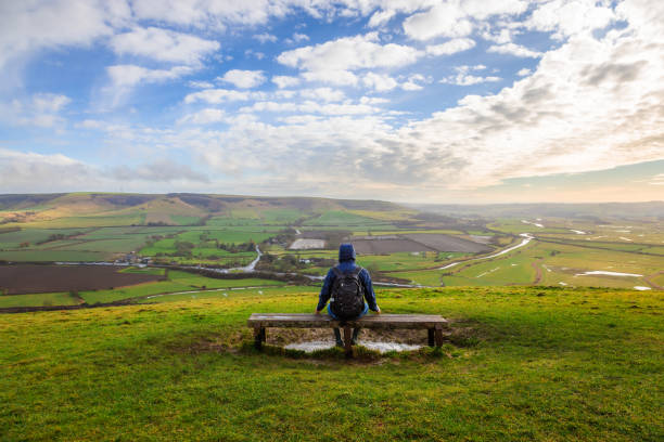 istock Hiker sitting on bench looking at view on South Downs in southeast England 2203399125