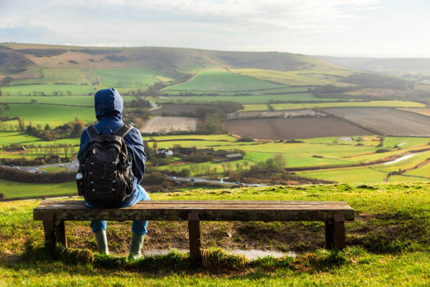 istock Hiker sitting on bench looking at view on South Downs in southeast England 2203399154