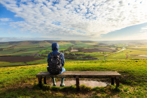 istock Hiker sitting on bench looking at view on South Downs in southeast England 2203399188