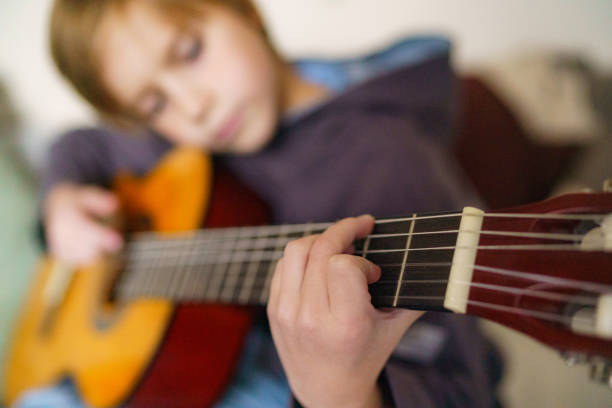 istock Close-up of boy playing guitar 2203399369