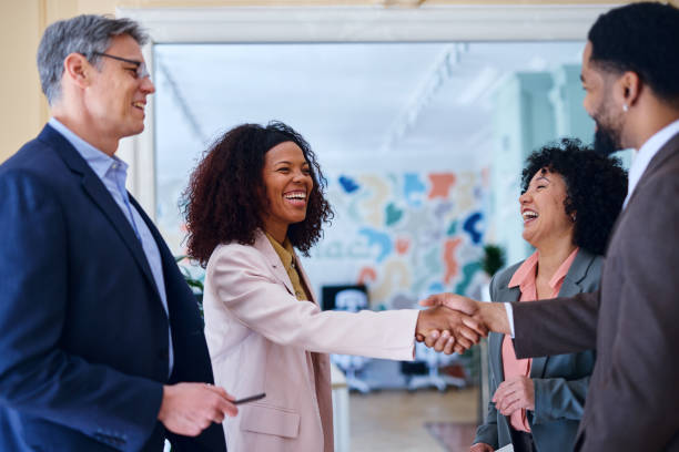 istock Businesswomen shaking hands while colleagues are looking at them, smiling 2203401230