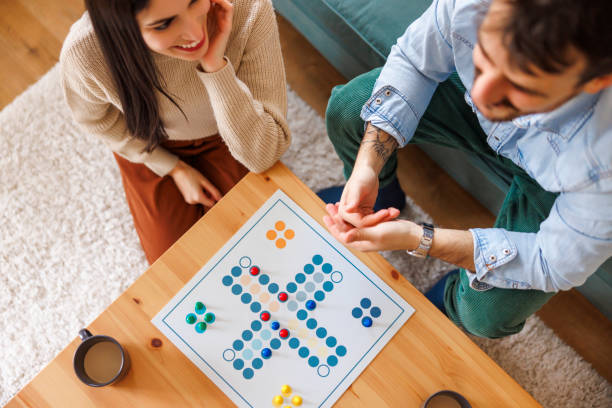 istock Couple enjoying spending leisure time together at home playing ludo board game 2203401301