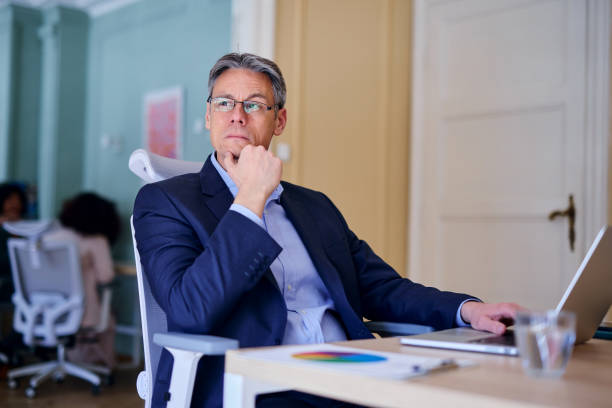 istock Pensive businessman working with laptop in modern office 2203401330