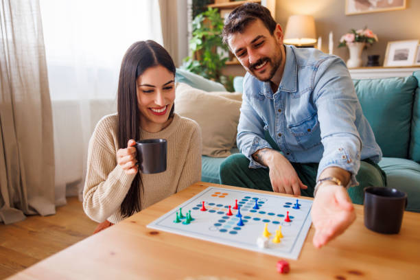 istock Couple playing ludo board game while spending leisure time at home 2203401350