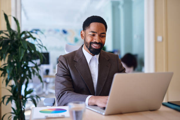 istock Smiling businessman working on laptop in modern office 2203401367