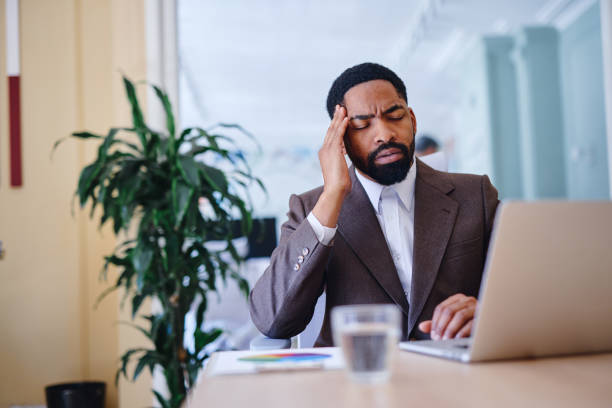 istock Stressed businessman having a headache while working on laptop in modern office 2203401417