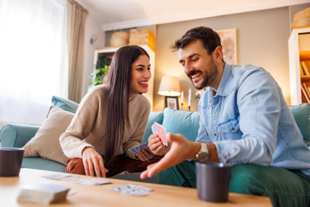 istock Beautiful multi-ethnic couple having fun playing card games at home 2203401439