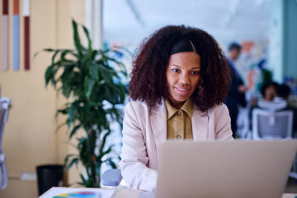 istock Confident businesswoman working on laptop in modern office 2203401454