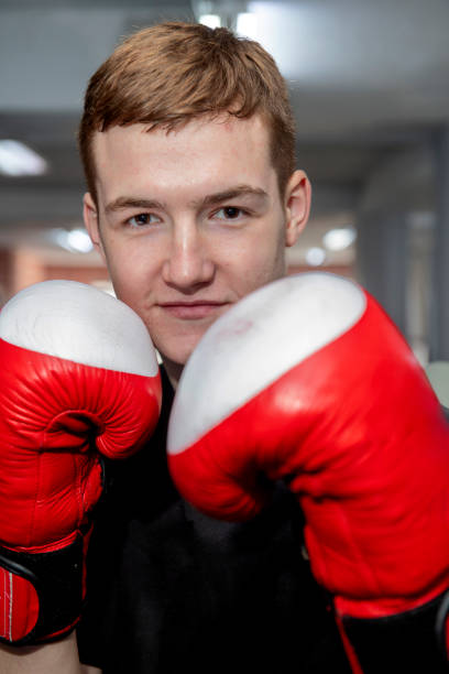istock Young boxer wearing red boxing gloves posing in gym 2203401979