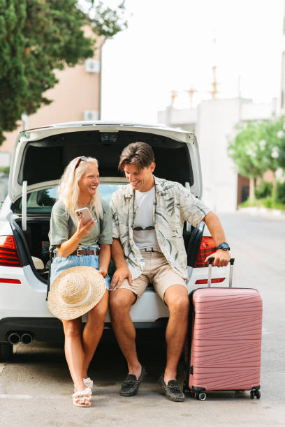 istock Young couple sitting by an open car trunk 2203402639
