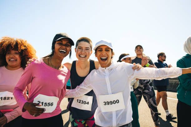 A diverse group of enthusiastic runners celebrate on race day, capturing a moment of joy and camaraderie. The joyful expressions and race numbers highlight their excitement and accomplishment.