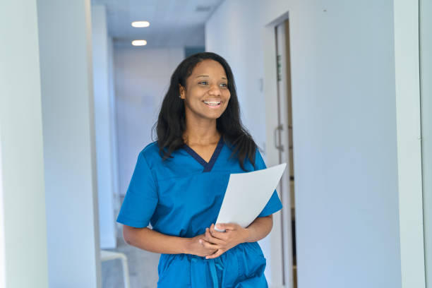 istock Smiling dentist walking through hospital corridor holding documents 2203407923