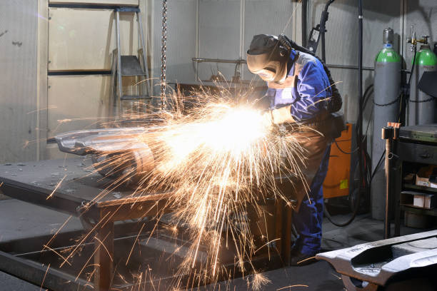 istock Workers in protective equipment in a foundry work on a casting with a grinding machine at the workplace 2203414475