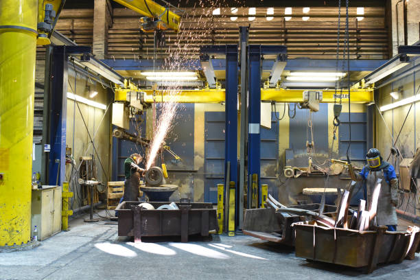istock Workers in protective equipment in a foundry work on a casting with a grinding machine at the workplace 2203414551