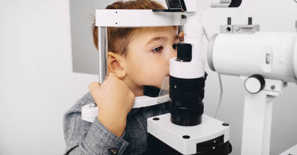 istock Young boy receiving a thorough eye examination using a slit lamp in a professional ophthalmology setting, focused on eye health 2203417728
