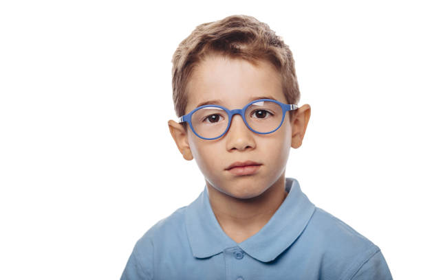 Young boy wearing blue glasses sits against a white background, emphasizing the importance of eye care and vision in childhood development.