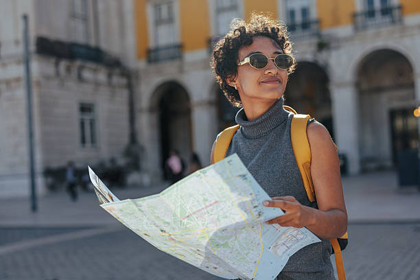Young woman consulting a map while enjoying her summer trip in lisbon, portugal, discovering the city's charming streets and architecture