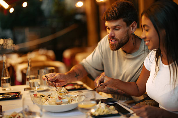 Couple enjoying dinner at a restaurant, eating salad