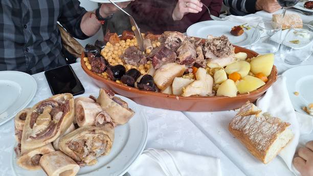 Traditional Madrid-style stew (Cocido Madrileño) with chickpeas, cabbage, chorizo, bacon, beef, chicken, blood sausage, potatoes, carrots, and ham, served on a table for several people