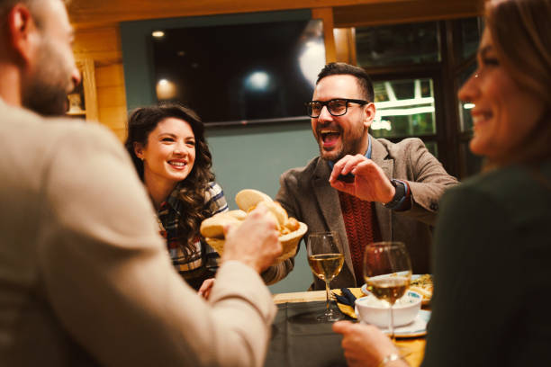 istock Cheerful friends sharing bread and wine laughing and having fun during a dinner at the restaurant 2203419310