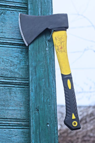 one big black yellow axe hangs on the green wooden wall of the house on the street