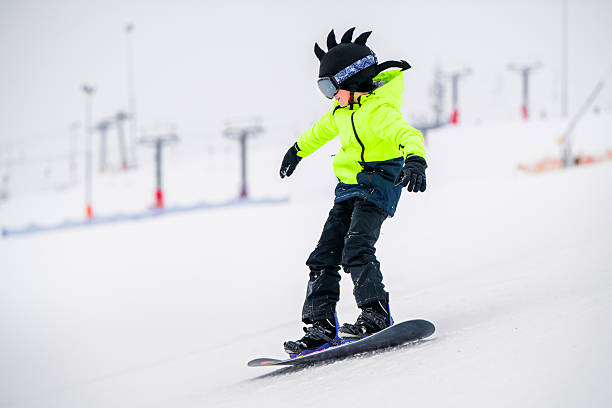 istock Young snowboarder in bright neon jacket riding downhill on snowy slope 2203420771
