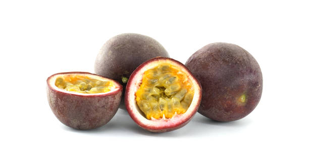 istock Fresh passion fruits and a half cut passion fruit showing its pulp and seeds on a white background 2203422028