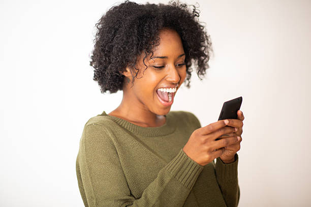istock Excited young black woman looking at mobile phone and smiling 2203422421
