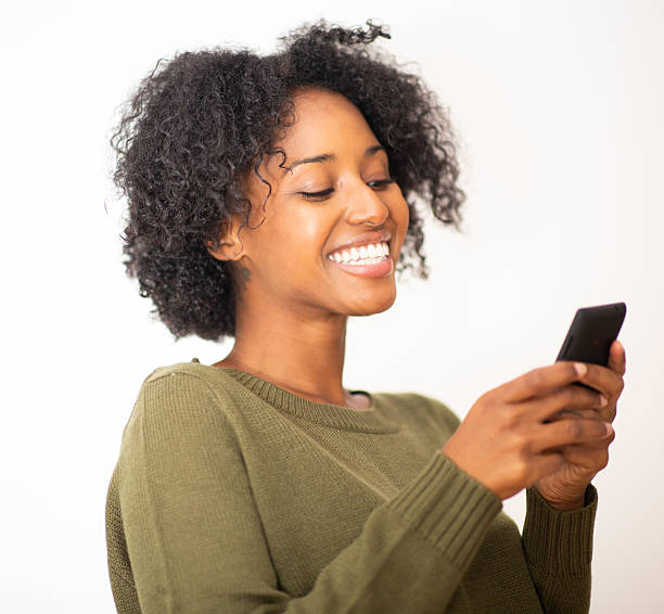 istock Happy young black woman looking at mobile phone on white background 2203422422