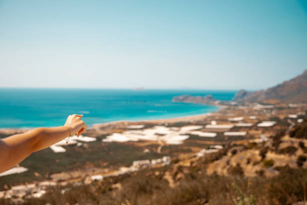Female Hand aiming to the beautiful blue sea coast. Coastal image, Summer Travel and Vacation, Ocean Waterfront. Copy space