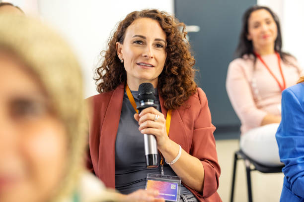 istock Professional woman asking questions in audience during conference event 2203423747