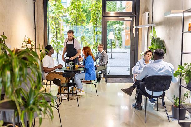 istock Business people sitting at cafeteria with waiter serving coffee 2203423905