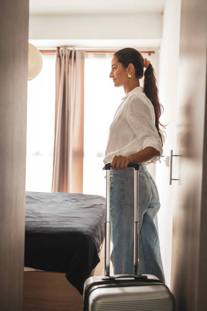 istock Woman standing with a suitcase inside a bright modern room 2203424608