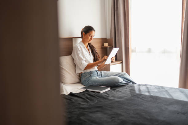 istock Young woman relaxing with a digital tablet on a cozy bed 2203424628
