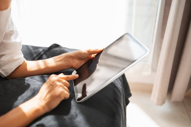 istock Close up of a Woman using a tablet with sunlight streaming through the window 2203424645