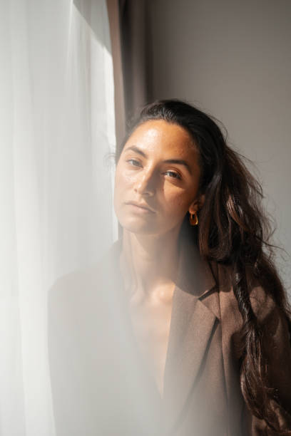 istock Serene woman gazing through sunlight wearing a blazer in a tranquil setting 2203424655
