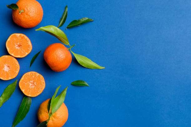 istock Many fresh ripe mandarin with green leaves on colored background, top view, space for text 2203432902