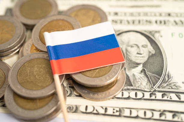 istock Stack of coins with Russia flag and US dollar banknotes. 2203433983