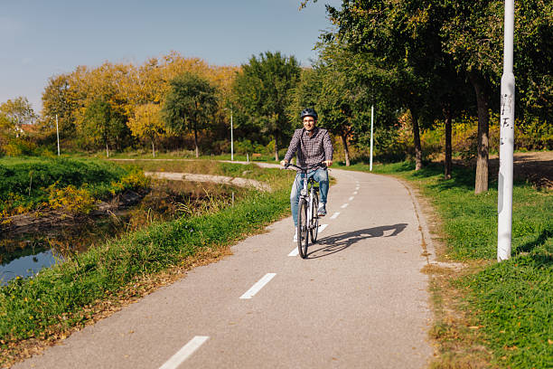 istock Young man riding bicycle in a park near a river during a sunny autumn day 2203437708