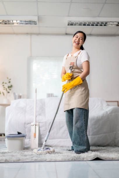 istock Smiling housekeeper mopping the floor in a modern bedroom, creating a bright and clean atmosphere in a cozy living space 2203438030