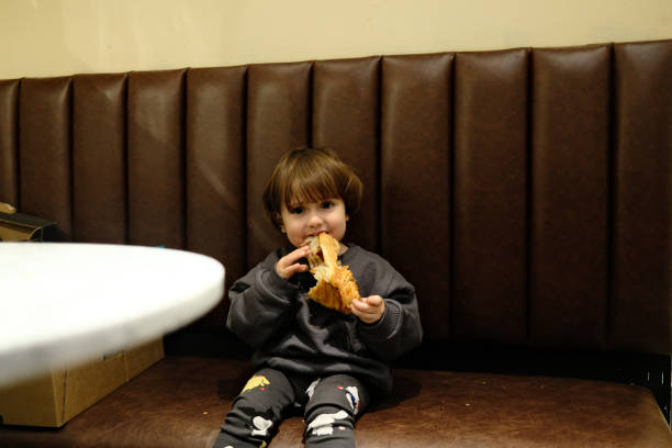 A toddler boy eating a slice of bread in the kitchen