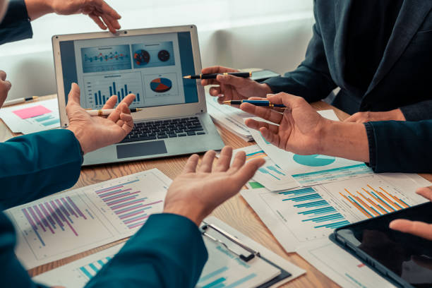istock Business alliance groups by analyzing documents, discussing reports at the board meeting table. A multi-ethnic team is negotiating a project to develop a business strategy. Close-up image. 2203440916