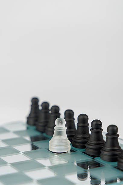 istock A white pawn stands alone against black pawns on a mirrored chessboard, symbolizing struggle, strategy, and resilience in opposition 2203443096